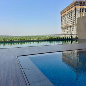 a swimming pool in front of a large building at Sky height 2BHK in GIFT CITY in Gandhinagar