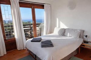 a bedroom with a white bed with a large window at Beach Cabin with a pool in Port Alfred