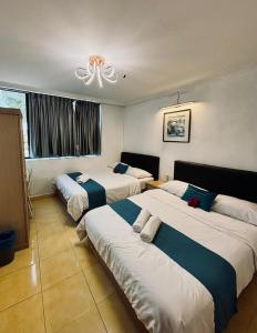 a hotel room with three beds and a window at Wangsa Village Inn in Ulu Tiram