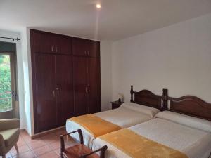 a bedroom with two beds and a chair and a window at El Secreto de Boada Spa privado & Restaurante Adults Only in Villamiel