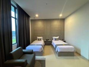 a hotel room with two beds and a couch at The Quadrant Hotel Ocarina Batam in Batam Center