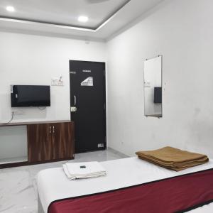 a room with a bed and a tv on the wall at Atithi Lodging in Ale