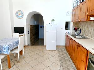 a kitchen with a table and a white refrigerator at Il Posto Giusto tra cielo e mare in Pantelleria +3 photos