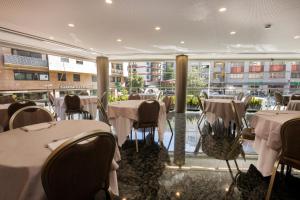 ein Restaurant mit Tischen und Stühlen und einem großen Fenster in der Unterkunft Hotel Nexta Escaldes in Andorra la Vella