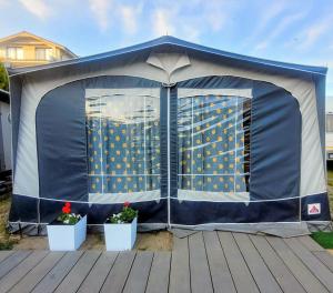 a blue tent with two potted plants on a deck at Surf Przyczepa Jastarnia in Jastarnia