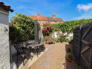 a patio with a table and chairs and flowers at Pankhurst Cottage in Louth