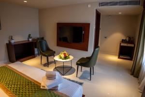 a room with a bed and two chairs and a table at Luxo Wayanad in Sultan Bathery