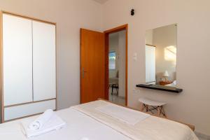 a bedroom with a white bed and a mirror at Beachside Apartment-2 in Afantou