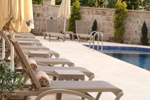 a row of chaise lounge chairs next to a swimming pool at Noble Blue Cappadocia in Ortahisar