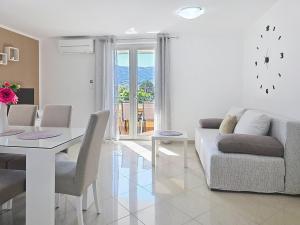 a white living room with a table and a couch at Apartments Gorica 2 in Baška