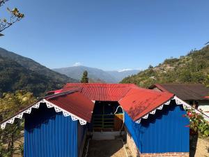 a house with blue doors and red roof at Karki Farm Stay in Bijanbāri Bāzār