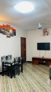 a room with a table and chairs and a flat screen tv at Varine House in Dodoma