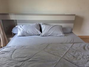a large bed with white sheets and pillows at The Plant Light Thiwanon in Lat Lum Kaeo