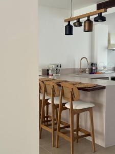 eine Küche mit Holzstühlen und einer Küchentheke in der Unterkunft Merichas Luxurious Villa in Kythnos