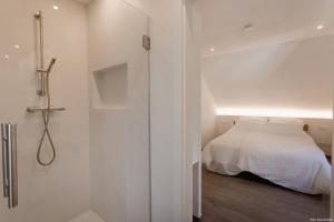 a white bedroom with a bed and a shower at Haus Auf der Zinn in Beilstein