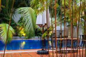 a pool with two chairs and a table and a umbrella at Samaya Boutique & Cuisine in Phnom Penh