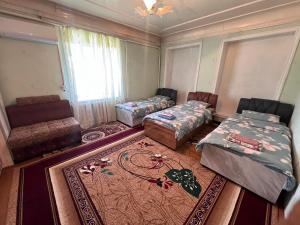 a room with two beds and a couch and a rug at Fazenda guest house in Oktyabrʼskoye