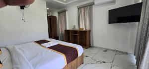 a bedroom with a bed and a flat screen tv at Brighton Stays in Sultan Bathery