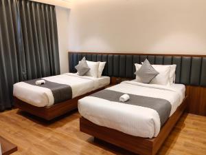 two beds in a hotel room at L G Cordial in Mysore +24 photos