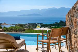 a patio with a table and chairs next to a pool at Elounda Heights (Adults Only) in Elounda