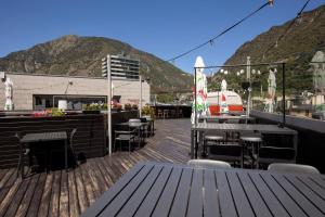 eine Terrasse mit Tischen und Stühlen auf dem Dach eines Gebäudes in der Unterkunft Hotel Nexta Escaldes in Andorra la Vella