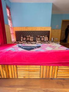 a bedroom with a bed with a red bedspread at Radhakrishna Homestay in Kulu