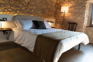 a bedroom with a white bed with a stone wall at Casale dei cappuccini in Scurcola Marsicana