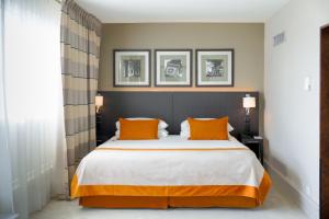 a bedroom with a large bed with two orange pillows at Auteuil Manotel in Geneva