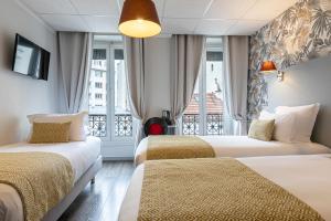 a hotel room with two beds and a balcony at Splendid Hôtel in Paris