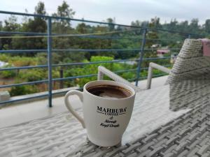 a cup of coffee sitting on a table on a balcony at Nice Hotel in Buknari