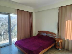 a bedroom with a purple bed and a large window at Nice Hotel in Buknari