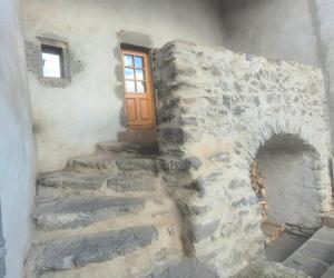 a stone building with a wooden door and stairs at L'Authentique - 5 Voyageurs - Château à 150m in Villeneuve