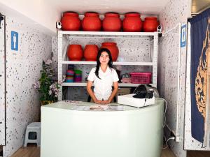 a woman standing behind a counter in a kitchen at Easy Monday Pool Capsule Hotel - Old Town Bangkok in Bangkok +65 photos