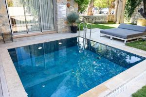 a swimming pool with blue water in a yard at Odette Pansiyon Bodrum in Bodrum City