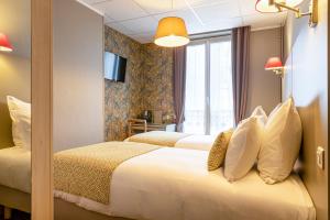 a hotel room with two beds and a window at Splendid Hôtel in Paris
