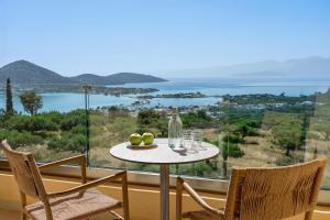 a table and chairs on a balcony with a view of the ocean at Elounda Heights (Adults Only) in Elounda