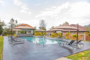 a swimming pool with chairs and umbrellas next to a house at MIRAMAR Ruhondo Resort in Muhororo