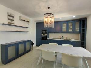 a kitchen with blue cabinets and a white table and chairs at Muo sea view Garden in Muo