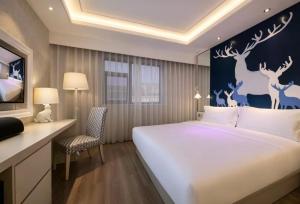 a hotel room with a large bed and a desk at Orange Hotel Beijing Shangdi Huandao in Beijing
