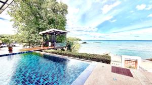 a swimming pool with a gazebo next to the water at Koh Sirey Beachfront Pool Villa in Phuket