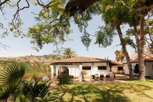 a house with a table and chairs in the yard at Cortijo Santa Cruz in Almuñécar