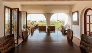 a room with a long table and chairs and windows at Cortijo Santa Cruz in Almuñécar