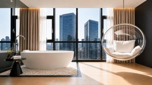 a bathroom with a tub and a chair in front of a window at 云涧江景酒店-重庆解放碑店 Chongqing Yunjian High-altitude River View Hotel-Jiefangbei Hongyadon in Chongqing