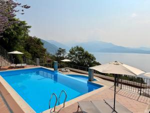 a swimming pool with an umbrella and a view of the water at Lakeview Residence in Oggebbio