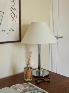 a lamp on a table with a book and glasses at Superbe Appartement ultra-centre climatisé in Vernon