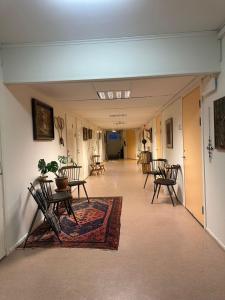 a hallway with chairs and tables and a rug at Örkelljunga Hostel in Orkelljunga