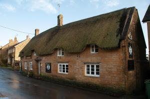 an old brick building with a thatched roof on a street at Mason's Arms in Montacute