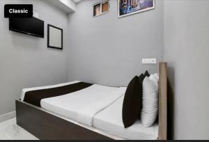 a bedroom with a bed with white sheets and black pillows at All sana guest house in Kolkata