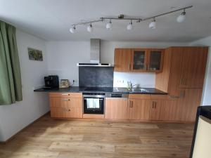 a kitchen with wooden cabinets and a black counter top at Ferienwohnung Wallersee in Neumarkt am Wallersee +15 photos