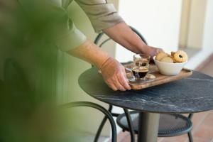 a person standing at a table with a tray of food and drinks at HB Boutique Apartment in Arco